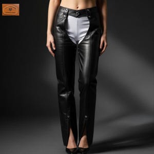 Puede incluir: Pantalones de cuero negro con cintura alta y un diseño frontal abierto único. Los pantalones tienen detalles de botones en la cintura y el tobillo, y se usan sobre tela blanca. Un artículo de moda elegante y atrevido.