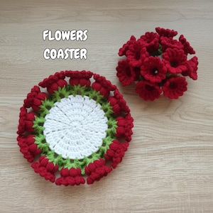 Könnte beinhalten: Zwei handgefertigte gehäkelte Blumenuntersetzer. Ein Untersetzer ist rund mit einer weißen Mitte, grünen Verzierungen und roten Blumenakzenten. Der andere ist eine Ansammlung roter gehäkelter Blumen. Der Text "FLOWERS COASTER" befindet sich oben links.
