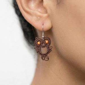 Könnte beinhalten: Ein Set aus drei Keramikbechern mit gesprenkelter, matter Oberfläche. Die Becher sind in Creme-, Hellgrau- und Dunkelgrautönen gehalten. Jeder Becher hat ein schlichtes, minimalistisches Design und einen abgerundeten Griff.