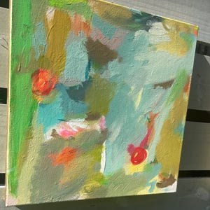 May include: Abstract painting on canvas with a vibrant mix of colors. The artwork features strokes of green, blue, yellow, orange, and red. The painting is mounted on a wooden frame, creating a modern art piece.