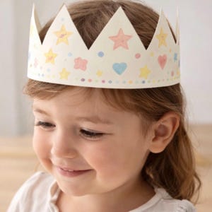 Könnte beinhalten: Eine Papierkrone mit gewelltem Rand, verziert mit pastellfarbenen Sternen, Herzen und Punkten. Die Krone wird von einem kleinen Kind getragen. Die Krone ist ein Party-Accessoire.