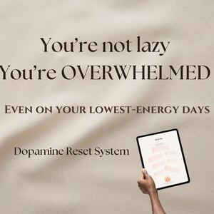 Może przedstawiać: Tablet z systemem produktywności, trzymany w dłoni. Ekran wyświetla ustrukturyzowany układ z tekstem i kształtami. Tło zawiera tekst "You're not lazy, You're OVERWHELMED" i "Dopamine Reset System".