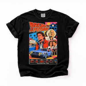 Könnte beinhalten: Ein schwarzes T-Shirt mit einem farbenfrohen Grafikdruck zum Film Zurück in die Zukunft. Das Design zeigt den Filmtitel, Charaktere, den DeLorean-Wagen und eine Zeitanzeige für das Ziel mit Oct 26 1985 01 21.