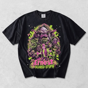 Może przedstawiać: Czarny t-shirt z krótkim rękawem z wyrazistym nadrukiem graficznym z filmu Ernest Scared Stupid. Wzór przedstawia dużego potwora, osobę w kamizelce oraz dziecko, wszystko w neonowych kolorach różu, zieleni i fioletu na czarnym tle.