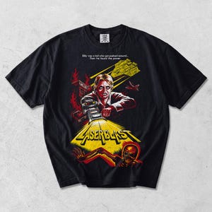 Pode incluir: Uma t-shirt preta de manga curta com uma impressão gráfica do filme Laserblast. O design mostra uma pessoa a segurar uma arma laser brilhante, um crânio, chamas e uma nave espacial, com o texto: Billy was a kid who got pushed around... Then he found the power e LASERBLAST.