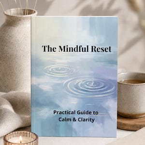 May include: A book titled The Mindful Reset: Practical Guide to Calm & Clarity with a cover illustration of blue water ripples. The book features a soft watercolour-style background in shades of light blue, white, and pale purple with text.