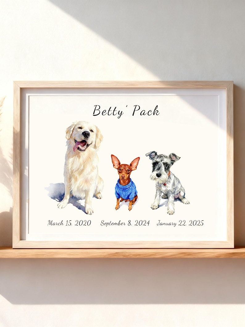 May include: A framed watercolor print featuring three dogs: a cream-colored Golden Retriever, a small brown dog wearing a blue sweater, and a grey and white Schnauzer. The text "Betty' Pack" appears at the top, with dates below each dog.