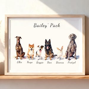 May include: A framed watercolor print titled Bailey' Pack featuring six dogs sitting in a row. The dogs are labeled with the names Ellie, Hugo, Biggie, Dan, Bianca, and Pretzel. The artwork is displayed in a light wood frame on a shelf.