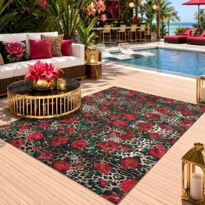 May include: Outdoor living space featuring a rug with a red rose and leopard print design. A white sofa with red and leopard print pillows sits near a round coffee table. Palm trees and a pool are in the background.