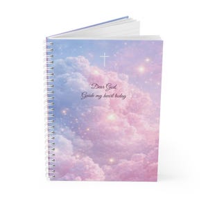 May include: Spiral-bound notebook with a cover featuring a dreamy sky design in shades of pink, purple, and blue. The cover includes a white cross and the text "Dear God, Guide my heart today."