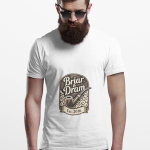 Pode incluir: Camiseta branca com um logotipo de estilo vintage. O logotipo diz "Briar & Dram" e apresenta um cachimbo de tabaco. O texto "Est. 2026" está em uma faixa. A camiseta é usada por uma pessoa com barba e óculos de sol.
