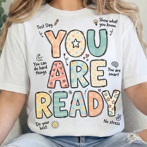 May include: White t-shirt with the words "YOU ARE READY" in colorful, whimsical letters. The design includes small illustrations and phrases like "Test Day," "You are smart," and "No stress."