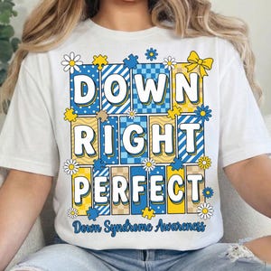 May include: White t-shirt with the words "DOWN RIGHT PERFECT" in large, colorful letters. The design includes puzzle pieces, daisies, and a yellow bow, with "Down Syndrome Awareness" printed below.