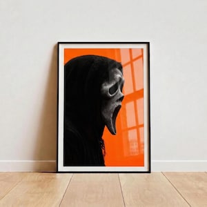 Puede incluir: Póster enmarcado con la icónica máscara de Scream en blanco y negro sobre un fondo naranja. La máscara es el punto focal, con su grito con la boca abierta. El póster está en un marco negro, agregando un toque moderno a la obra de arte de temática de terror.