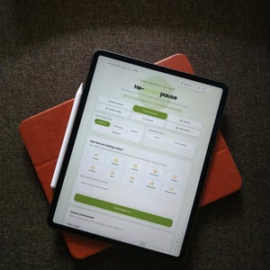 Puede incluir: Una tableta que muestra una interfaz de salud digital titulada He-Andropause con un lápiz óptico blanco sobre la pantalla. La interfaz presenta botones verdes y blancos para salud mental, estrés, sueño y un formulario de registro diario.
