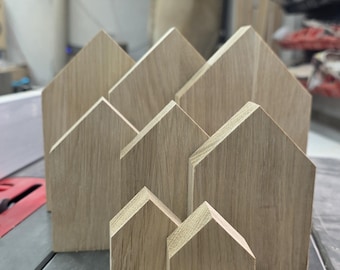 May include: A collection of wooden house-shaped blocks in varying sizes, arranged on a gray surface. The blocks are made of light-colored wood, showcasing the natural grain. The website address www.odwoodcraft.co.uk is visible at the bottom.