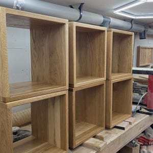 May include: Four square open-front wooden boxes constructed from light-coloured oak with a visible wood grain pattern. The boxes are arranged in two vertical stacks of two, featuring smooth edges and a natural finish, showcasing the joinery details.