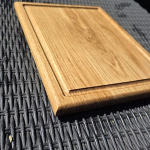 May include: A rectangular oak cutting board with a light brown finish and a recessed groove around the edge. The website address www.odwoodcraft.co.uk is visible at the bottom of the image.