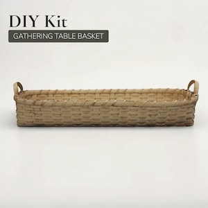 May include: A rectangular woven basket with two handles. The basket is made of light brown material and has a woven pattern. The text "DIY Kit" and "GATHERING TABLE BASKET" are displayed above the basket.