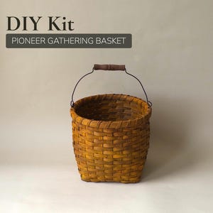 May include: A woven, yellow-brown basket with a dark handle and a black wire handle. The basket is labeled "DIY Kit" and "PIONEER GATHERING BASKET" in a dark gray rectangle. The basket is made of woven material.