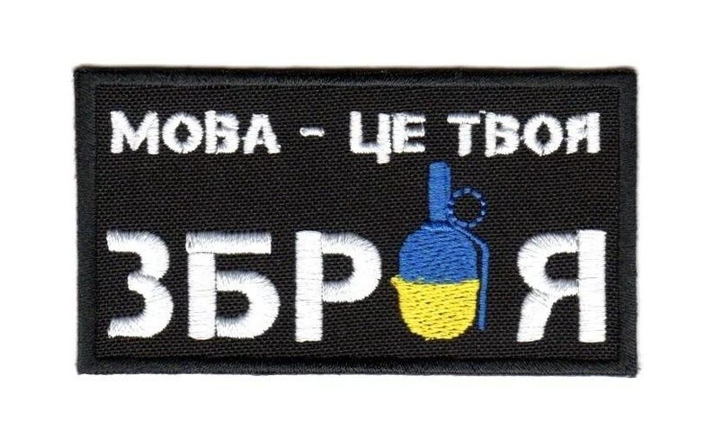 May include: Black rectangular patch with white embroidered text and a grenade graphic. The text reads "MOBA - TSE TVOI ZBROYA" with a blue and yellow grenade illustration, likely representing a political or military theme.