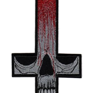 May include: An embroidered patch in the shape of an inverted cross. The design features a grey skull integrated into the cross structure, with red thread detailing that mimics dripping blood flowing down from the top of the cross over the skull.