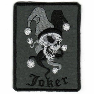 May include: Embroidered patch featuring a skull wearing a jester's hat, with the word "Joker" below. The skull is detailed in white thread, set against a dark gray background with a black border. The jester's hat is black and gray.