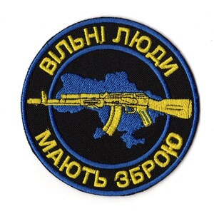 Può includere: Toppa ricamata con sfondo nero e design blu e giallo. La toppa presenta un contorno blu dell'Ucraina, un fucile AK-47 giallo e testo giallo in un motivo circolare che recita "Le persone libere hanno armi."