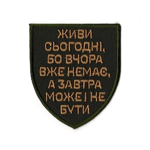May include: A dark green patch with gold embroidered text in a shield shape. The text reads in Ukrainian: "Live today, because yesterday is gone, and tomorrow may not be." The patch has a dark green border.