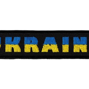 May include: A rectangular embroidered patch with a black border featuring the word UKRAINE in block letters. Each letter is split horizontally with a bright blue top half and a vibrant yellow bottom half, mimicking the colours of the national flag.