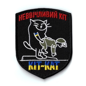 May include: Black embroidered patch with a cat graphic and the text "НЕВВІЧЛИВИЙ КІТ" in red. The cat is depicted in a humorous pose with a soldier. The text "KIT-KAT" is also present in yellow and blue.
