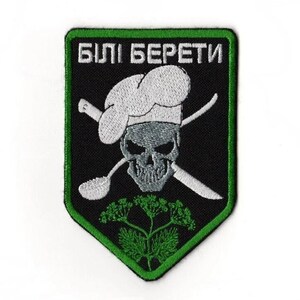 Puede incluir: Parche bordado con fondo negro y borde verde. El parche presenta una calavera con gorro de chef, cuchara y cuchillo cruzados, y el texto "БІЛІ БЕРЕТИ" en blanco. Un diseño de planta verde en la parte inferior.
