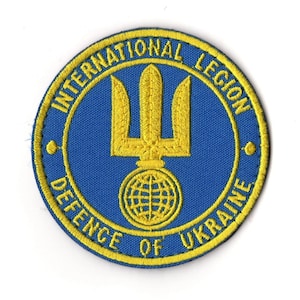 May include: Embroidered patch with a blue background and yellow text and accents. The text reads "INTERNATIONAL LEGION DEFENCE OF UKRAINE." The central design features a yellow trident above a globe.
