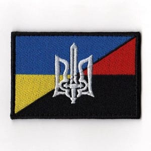 Puede incluir: Parche bordado con un diseño de tridente blanco sobre un fondo rectangular. El parche está dividido en secciones azules, amarillas, rojas y negras. Tiene un borde negro.