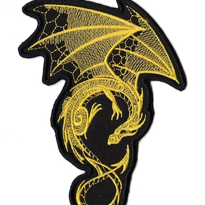 Könnte beinhalten: Ein gestickter Aufnäher mit der Silhouette eines gelben Drachen auf schwarzem Hintergrund. Der Drache ist in einer eingerollten Position mit nach oben ausgebreiteten Flügeln dargestellt, mit detaillierten Stickereien und einem schwarzen Rand.