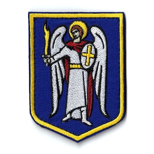 Puede incluir: Parche bordado con diseño de escudo, fondo azul y borde amarillo. Representa un ángel sosteniendo una espada dorada y un escudo con una cruz. El ángel viste túnicas blancas y tiene un halo dorado.