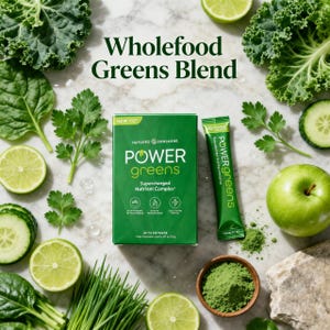 A vibrant product photo titled "Wholefood Greens Blend" featuring a box of Power Greens and a single-serve stick packet. Surrounded by fresh kale, spinach, cucumbers, green apples, and limes, highlighting its natural and nutrient-dense formula.