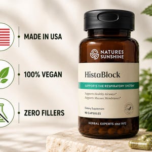 May include: A brown glass bottle of HistaBlock capsules with a black lid, set on a stone surface. The label indicates it supports the respiratory system and is made in the USA, 100% vegan, and contains zero fillers. Green capsules are scattered nearby.