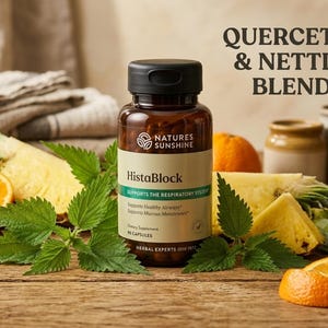 May include: A brown bottle of "HistaBlock" supplements with a black cap, surrounded by fresh pineapple, orange slices, and green leaves. The label reads "Quercetin & Nettle Blend" and "Supports the Respiratory System".