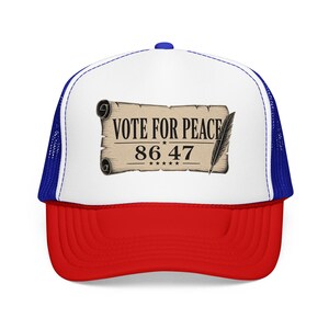 May include: A red, white, and blue trucker hat with a curved brim. The front panel displays a scroll with the text "VOTE FOR PEACE 86 47" and a feather illustration. The hat has a mesh back and a snap closure.