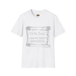 May include: White t-shirt featuring a gray scroll design with the text "We the People HAVE HAD ENOUGH!". The shirt has a crew neck and short sleeves. The design is centered on the front of the shirt.