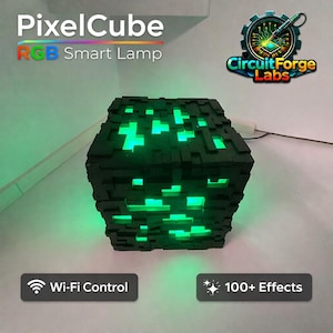 May include: A black PixelCube RGB Smart Lamp with green glowing pixelated sections. The lamp has a cube shape and the text "PixelCube RGB Smart Lamp" is at the top. The lamp is Wi-Fi controlled and has 100+ effects.