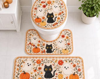 May include: A three-piece bathroom mat set featuring a toilet seat cover, a U-shaped contour rug, and a rectangular bath mat. Each piece has a cream background with a pattern of black cats, white ghosts, orange pumpkins, and autumn flowers.