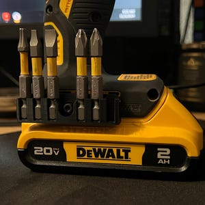 May include: A yellow and black DeWalt cordless drill with a 20V battery. The drill has a black bit holder with several metal drill bits. The DeWalt logo is prominently displayed on the battery.