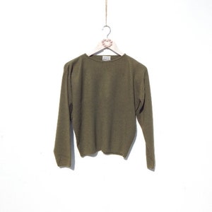Può includere: Un maglione verde oliva a maniche lunghe con collo rotondo.