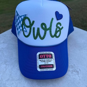 May include: A blue and white trucker hat featuring a white foam front panel with the word Owls in green glitter script. A blue and white checkered star is on the left, a blue heart is on the right, and an Otto brand sticker is on the blue brim.