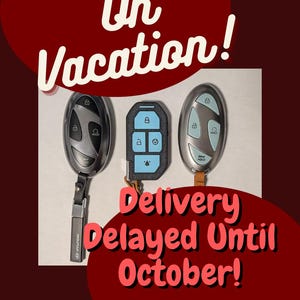 May include: Three car key fobs arranged in a row. The two outer fobs are oval-shaped, silver, and black with various lock and unlock icons. The center fob is rectangular, black, and light blue with five buttons. Text reads On Vacation! Delivery Delayed Until October!