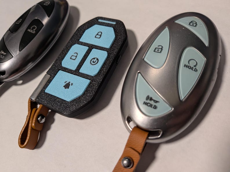 Puede incluir: Tres mandos de coche. Uno es plateado con botones negros, otro es negro con botones azul claro y otro es plateado con botones azul claro. Dos de los mandos cuentan con correas de cuero marr&oacute;n con remaches met&aacute;licos plateados.