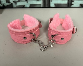 Puños de muñeca ajustables de piel sintética con felpa rosa.