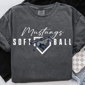 May include: Dark gray sweatshirt with the words "Mustangs SOFTBALL" in white script and block letters. A navy blue horse graphic is inside a white home plate shape. The sweatshirt has long sleeves.